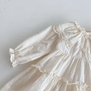 Primo piano dettagliato del vestito da bambina color crema con colletto in pizzo.