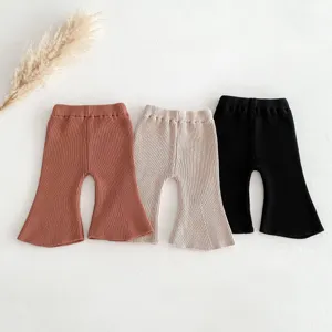 Detailed view of baby knitted flare pants in three colors, soft cotton fabric texture.