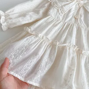 Dettaglio di un grazioso vestito bianco a maniche lunghe a balze per bambina con colletto in pizzo.