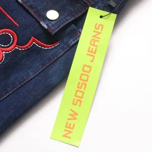Details van herenjeans met contrasterend borduurwerk en heldergroen productlabel.