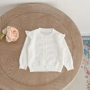 Detail shot of white baby girl knitted cardigan with delicate hollow-out lace ruffle trim.