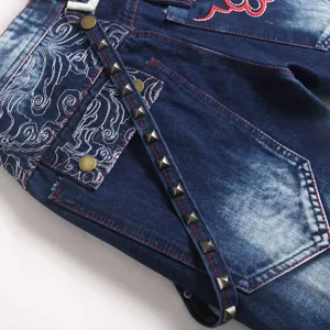 Detailopname van blauwe gewassen spijkerbroek voor heren met fijne borduursels en metalen studs.