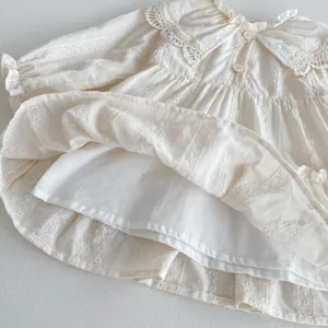 Primo piano sui dettagli del vestito per bambina con colletto in pizzo e volant a strati.