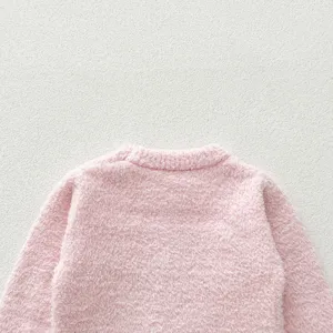 Close-up view of a soft pink fluffy baby sweater, showing cozy texture and round neckline.