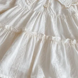 Primo piano dettagliato di un vestito bianco a balze per bambine con colletto in pizzo delicato.