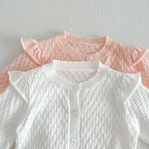 Close-up detail of girls knit cardigan, featuring sweet ruffles, flower buttons and airy knit.