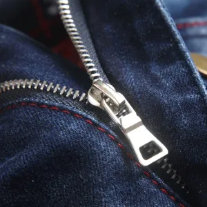 Heren denim jeans close-up detail, donkerblauwe gewassen stof met contrasterende rode stiksels.