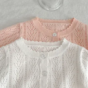 Primo piano del cardigan in maglia di coton per neonati con motivo traforato e bottoni.