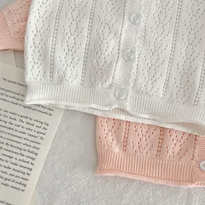 Cardigan in maglia traforata di cotone per neonati dettaglio, texture morbida stile dolce.