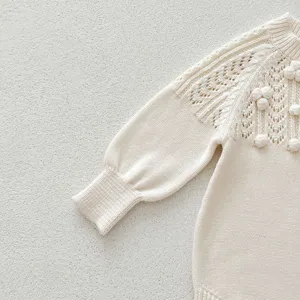 Close-up detail of infant knit sweater, hollow-out pattern and cute bobble decorations.