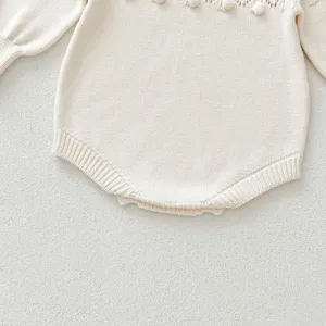 Detailed view of baby girl knitted romper featuring cute hand-crochet bobbles and hollow-out design.