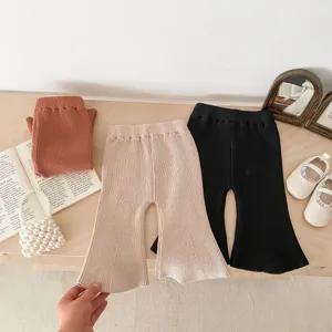 Detailed shot of baby knitted flare pants in neutral tones, displayed on a wooden table.