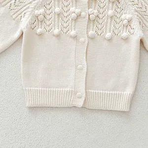 Infant baby knitted cardigan detail, cute pom-pom and hollow knit pattern, soft button-up.