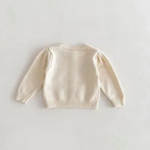 Back view detail of baby knit cardigan in cream color with cute puff sleeves and ribbed hem.