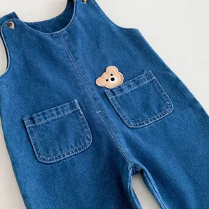 Close up of baby denim overall bib trousers with cute bear embroidery pocket detail child wear
