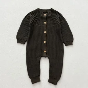 Detailed view of baby knitted romper in dark green with wooden buttons and cozy long sleeves.