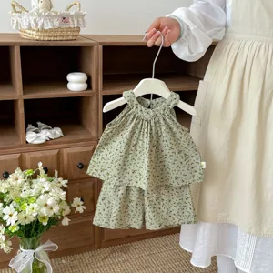 Ensemble deux pièces bébé à fleurs vertes, haut dos-nu mignon et short assorti en détail.