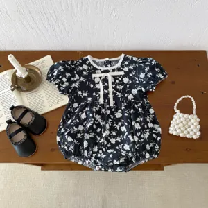Detailansicht von Baby Mädchen blumigen Kurzarm Strampler mit weißer Schleife flachgelegt.