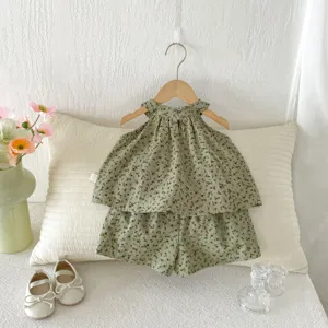 Detail en gros plan de ensemble deux pieces bebe ete floral vert, haut sans manches et short.
