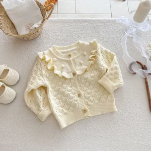 Chic baby girl knit cardigan with ruffle collar, hollow design and cute pom-poms in cream.