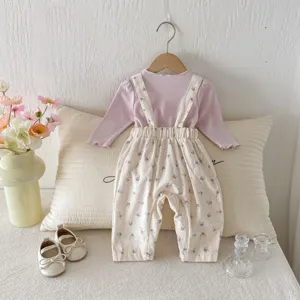 Detailansicht des Baby Herbstoutfits, lila Oberteil und Blumen Latzhose mit Dekoration.