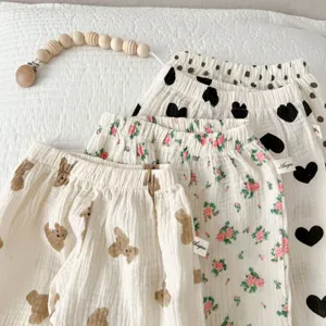 Close-up of infant gauze pants detail, cute bear and floral prints, soft breathable fabric.