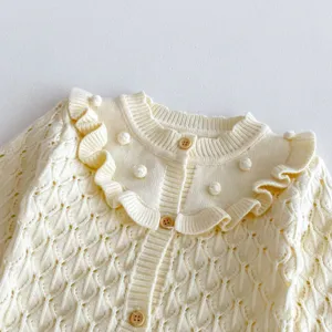 Close-up detail of baby girl knit cardigan, rufflar collar, hollow-out pattern, sweet view.