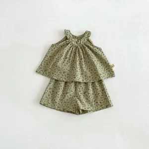 Détail d'ensemble de vêtements pour enfants à fleurs vertes, haut sans manches et short assorti.