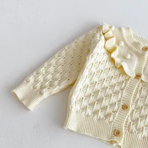 Close-up of cream baby girl knit cardigan with delicate ruffles, hollow design, and sweet buttons.