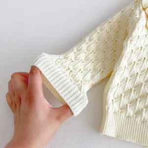 Infant baby knit cardigan sleeve detail, cream white hollow out knitwear, soft ribbed cuff design.
