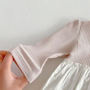 Détail de tissu haut de printemps pour fillette, manches longues côtelées roses et dentelle.