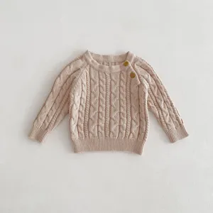 Closeup of baby cable knit sweater texture, soft cotton fabric, cute shoulder button detail.