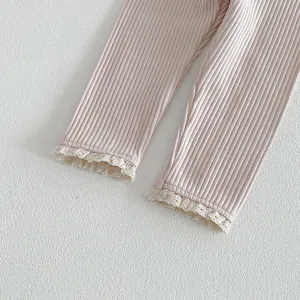 Gros plan de détails de leggings côtelés pour filles avec bordure en dentelle blanche.