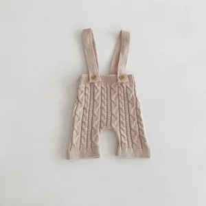 Detailed view of baby cable knit suspender shorts, soft cotton material texture and cute buttons.