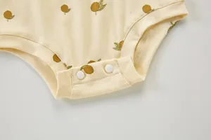 Primer plano detalle de mameluco para bebé con lindo estampado de frutas y botones.