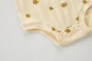 Vista de detalle en primer plano de mameluco de verano para bebé, lindo estampado y botones.