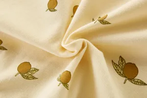 Detalle de tela de mameluco para bebé, algodón amarillo claro con estampado de limón