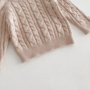 Detailed shot of baby cable knit pullover sweater, soft texture, cozy infant fall spring wear.