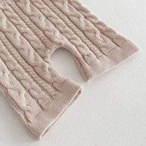 Baby cable knit romper detail shot, soft pink texture closeup, gentle infant apparel design.