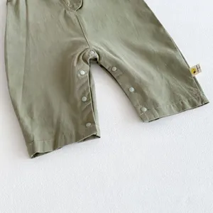Detailed view of green baby jumpsuit featuring convenient snap buttons and side brand label.