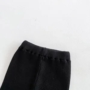 Close-up detail of black knitted baby pants waistband, soft cotton yarn fabric, toddler wear.