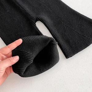 Detailed shot of baby black knit flare pants, showing soft ribbed cotton texture detail.