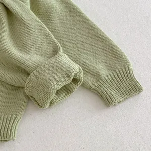 Close-up detail of mint green baby knit sweater sleeve, soft cotton yarn texture.