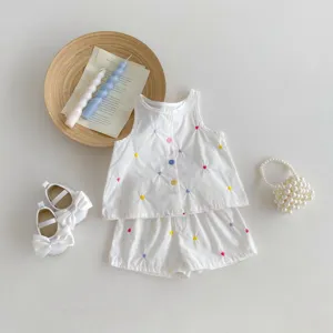 Dettaglio outfit estivo per neonata, top bianco smanicato con ricami di cuori colorati.