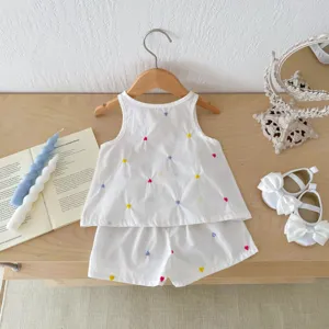 Dettaglio outfit estivo in cotone per bambina, cuori colorati ricamati su top bianco.