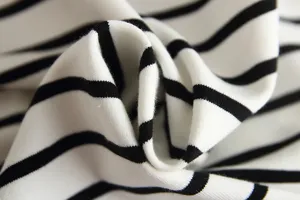 Close-up detail view of soft black and white striped cotton fabric for baby autumn clothing.