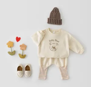 Detailed view of cute infant sweatshirt and pants set with bear graphic and matching knit hat.