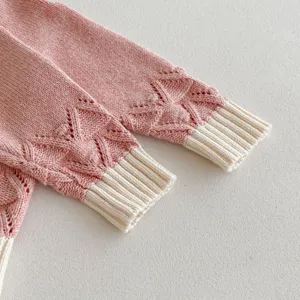 Close up view of cute baby girl pink knit cardigan sleeve with hollow pattern and white cuffs.