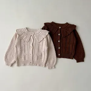 Detailed shot of infant knitted cardigan featuring doll collar, textured knit and cute buttons.