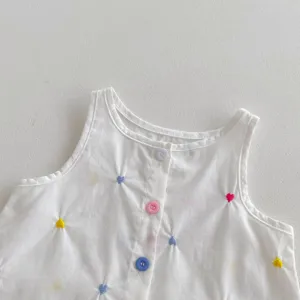 Primo piano del top senza maniche in cotone per bambina, con ricami a cuore e bottoni colorati.